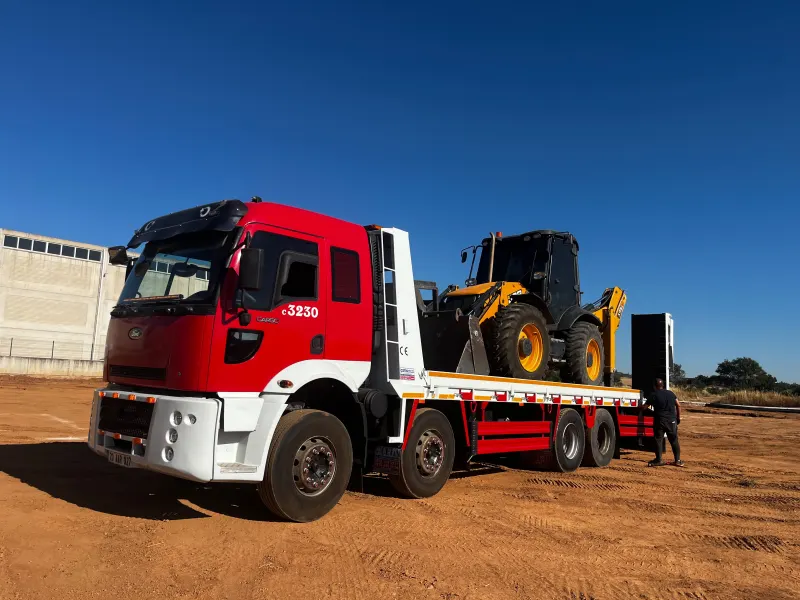 Kırmızı tamburlu çekici (lowbed) üzerinde kazıcı yükleyici
