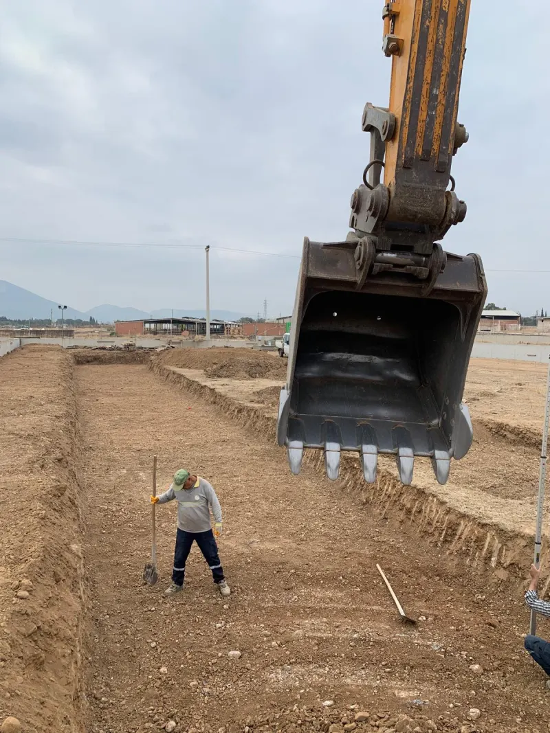 Temel kazısında ekskavatör kovası, sahada çalışan usta